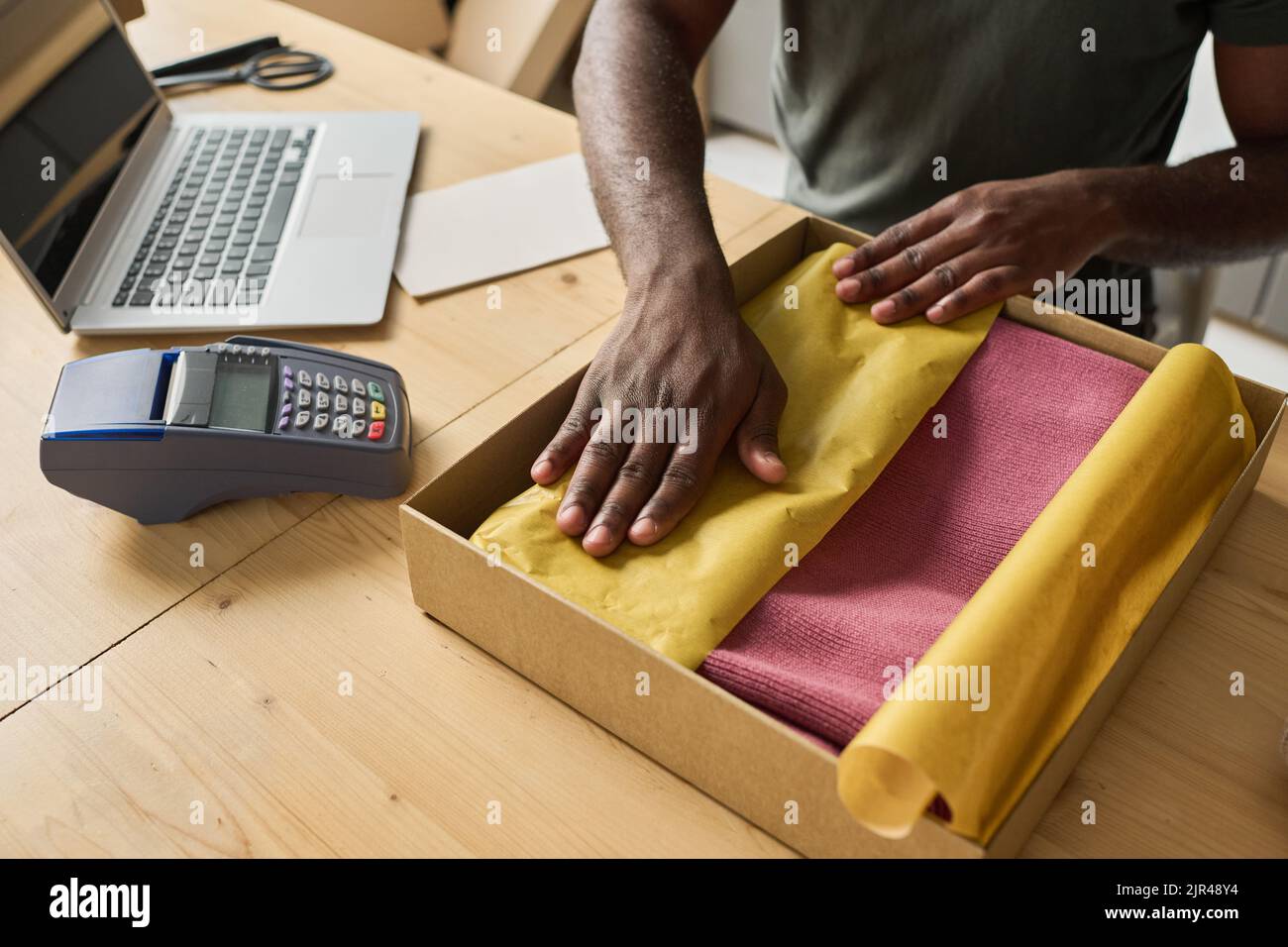 High angle view of worker packing new clothes in cardboard box at table to make parcel for delivery Stock Photo
