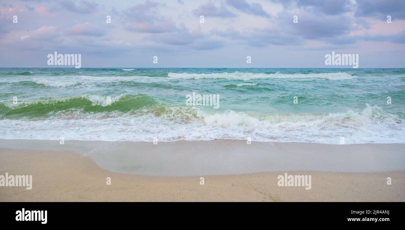 velvet season seascape. waves rushing on the beach. cloudy sky before the evening storm Stock Photo