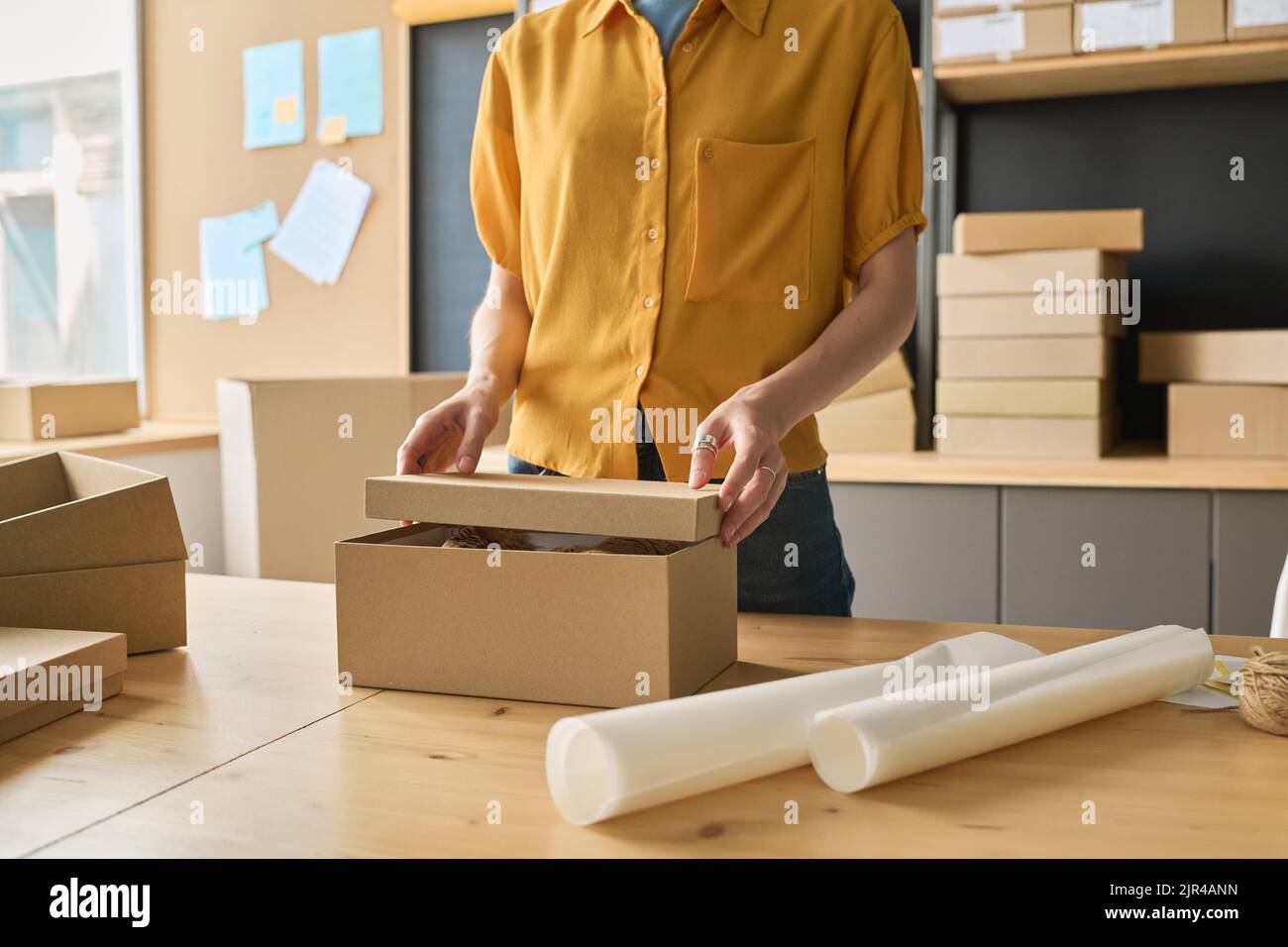 Closeup of young female worker closing the cardboard box and finishing