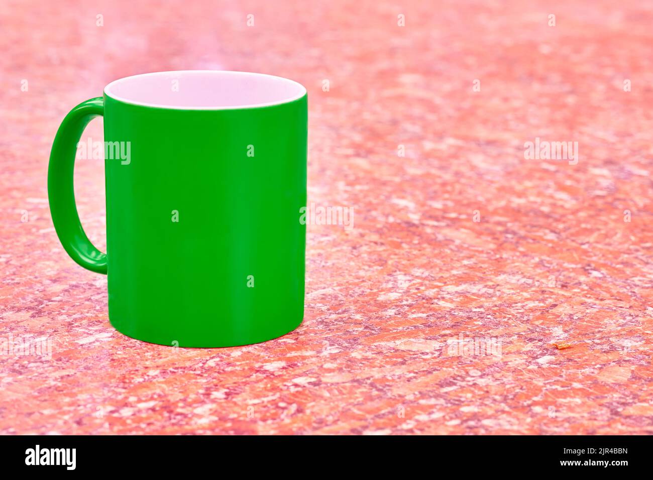 Green ceramic cup mug on bright red white spotted background Stock Photo