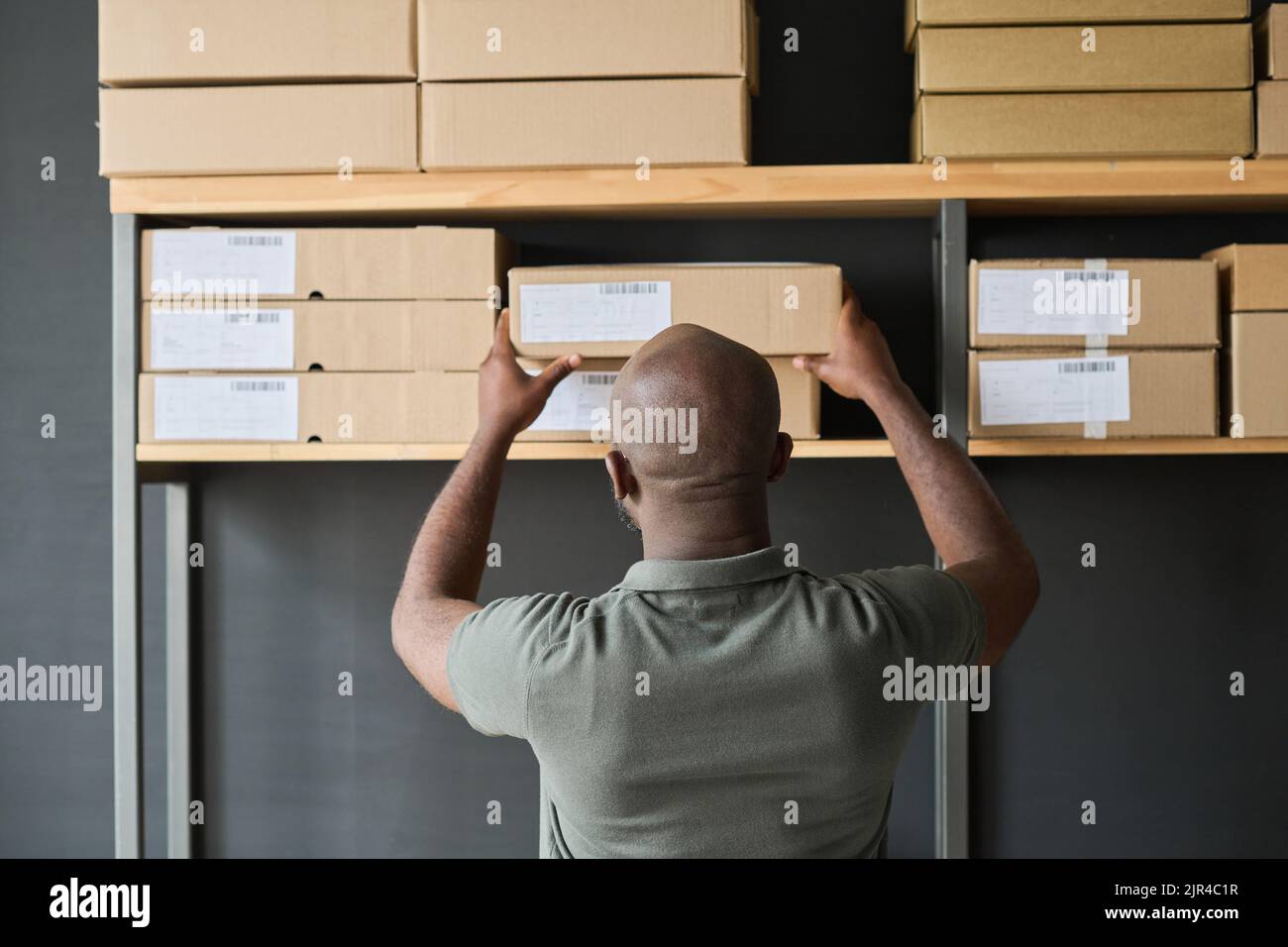 Asian guy organizing boxes with supplies on shelves Stock Photo by DC_Studio