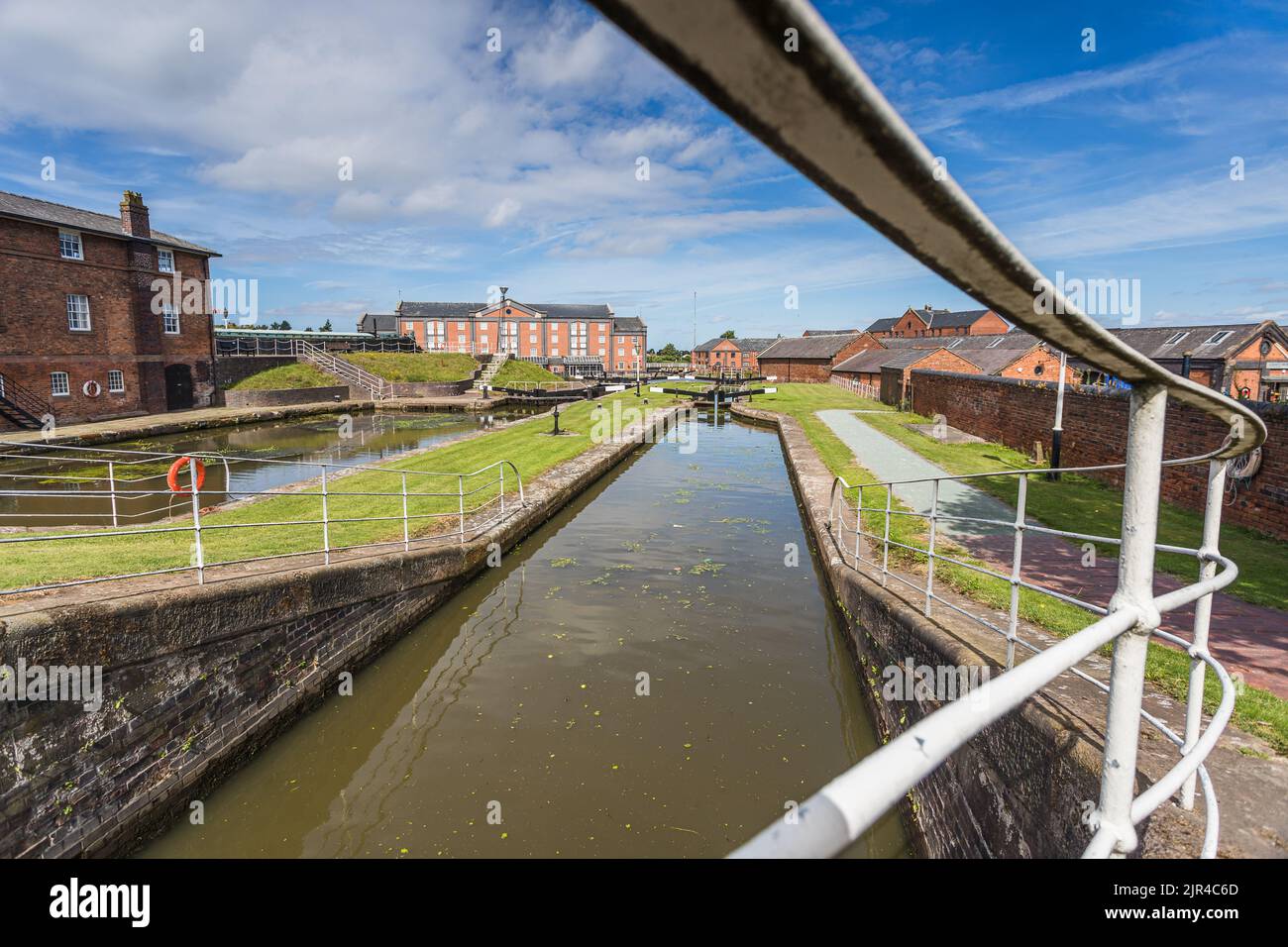 Looking along the railings which enclose one of the canal locks at Ellesmere Port, Cheshire seen in August 2022. Stock Photo