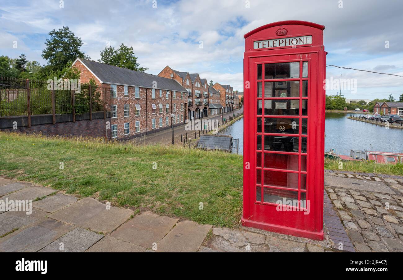 Old red telephone box seen in front of Ellesmere Port canal basin in Cheshire in August 2022. Stock Photo
