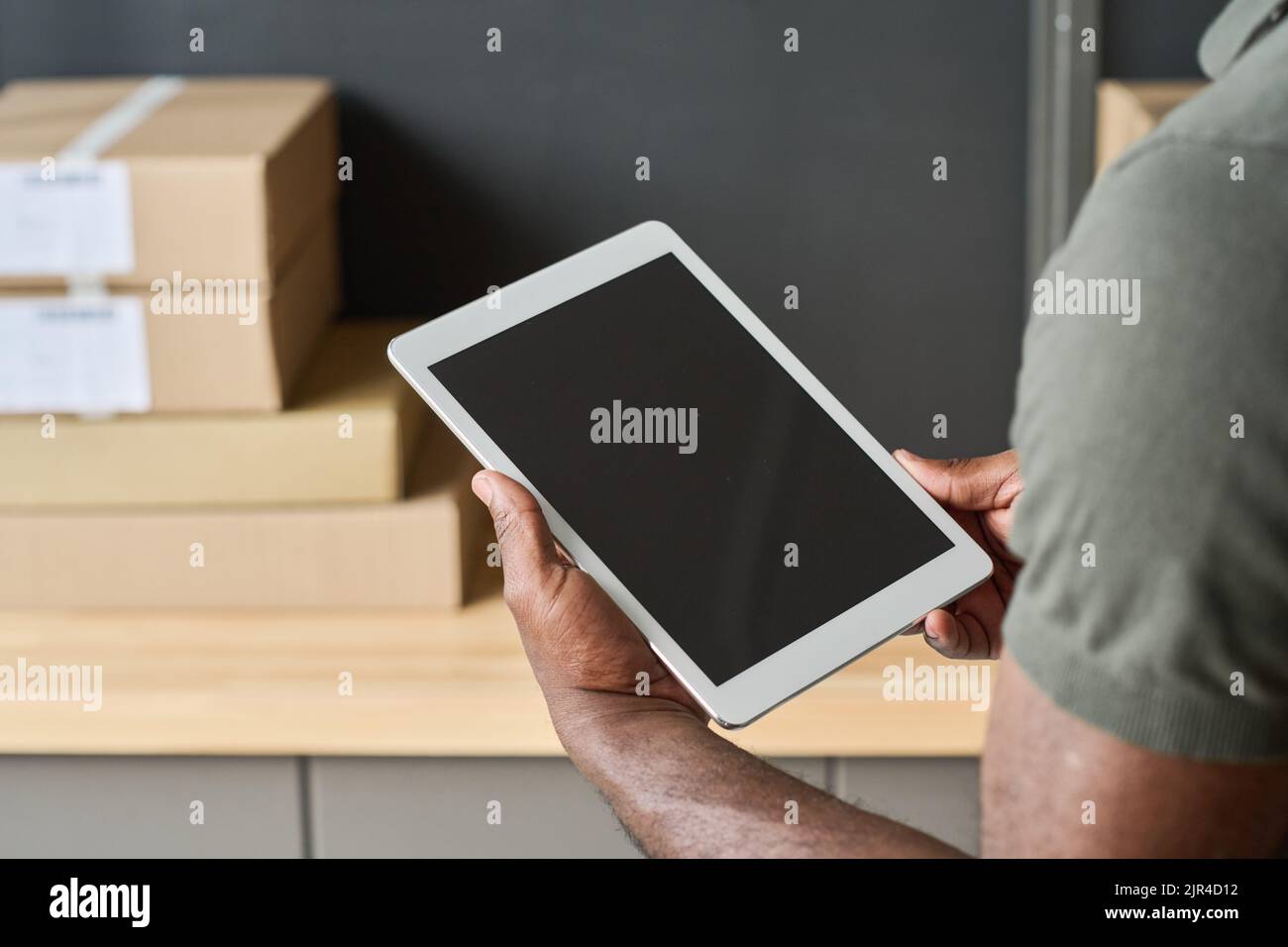 Close-up of warehouse worker checking track numbers of parcels on digital tablet during his work in warehouse Stock Photo