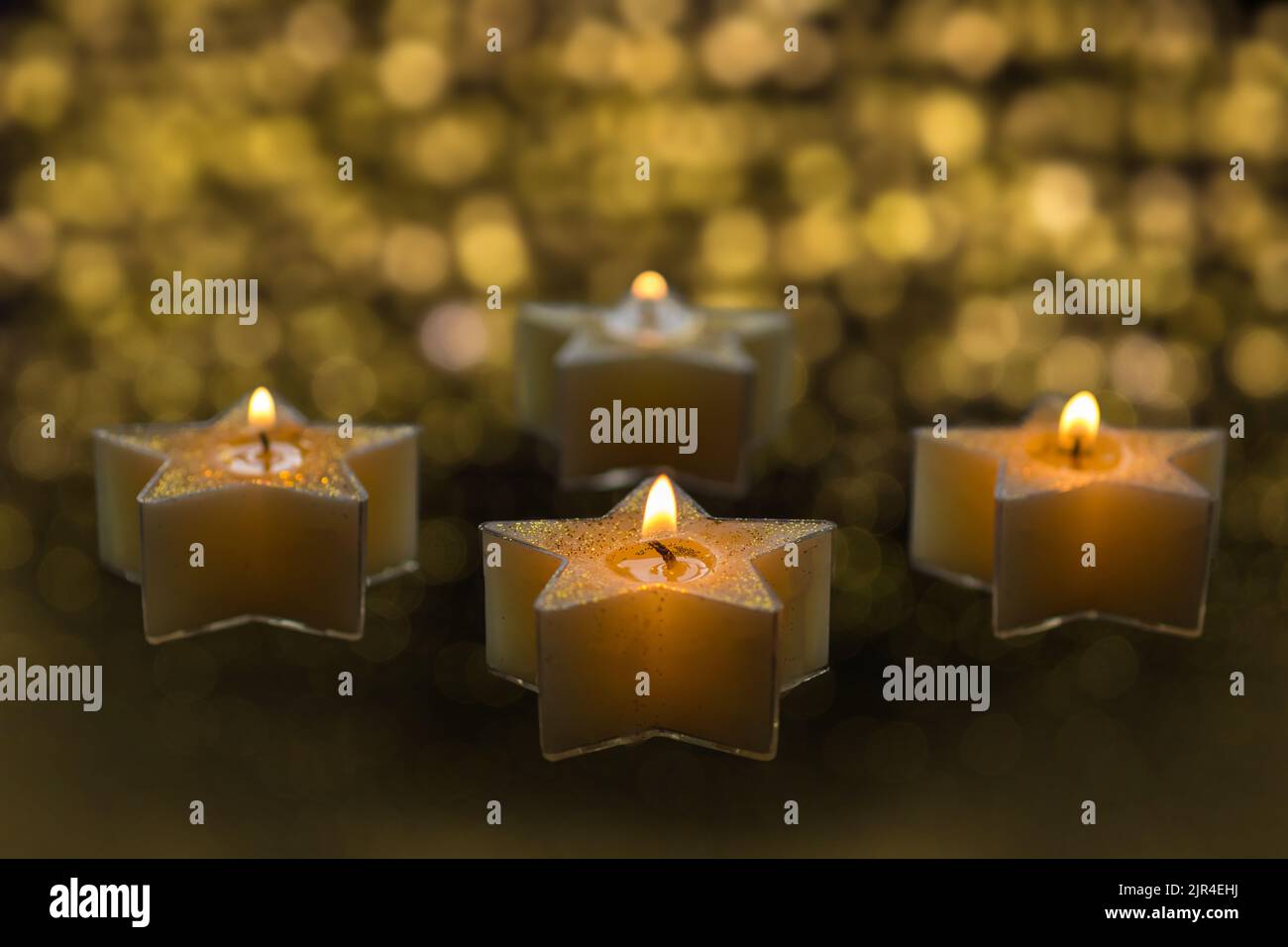 Four star shaped candles are burning in the dark Stock Photo