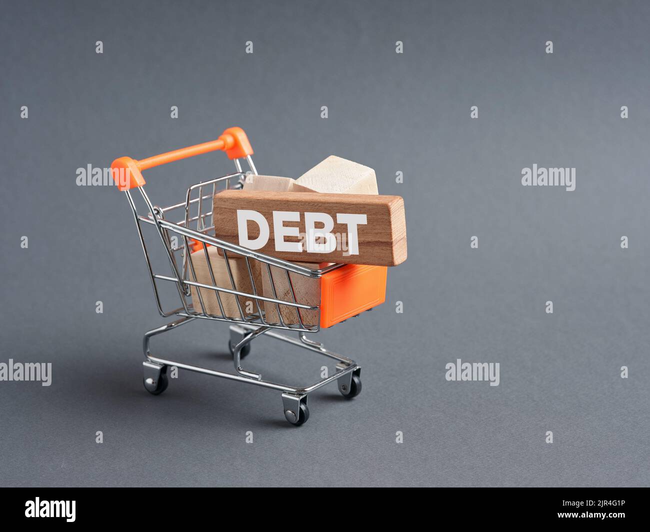Wooden blocks with the word Debt in a shopping cart. Consumerism, inflation and rising costs and expenses. Household budget deficiency. Stock Photo