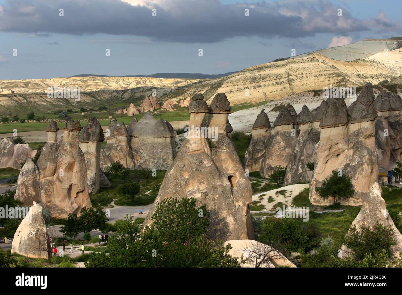 Tourists wander amongst a series of volcanic rock formations known as fairy chimneys at Pasabagi near Zelve in the Cappadocia region of Turkey. Stock Photo