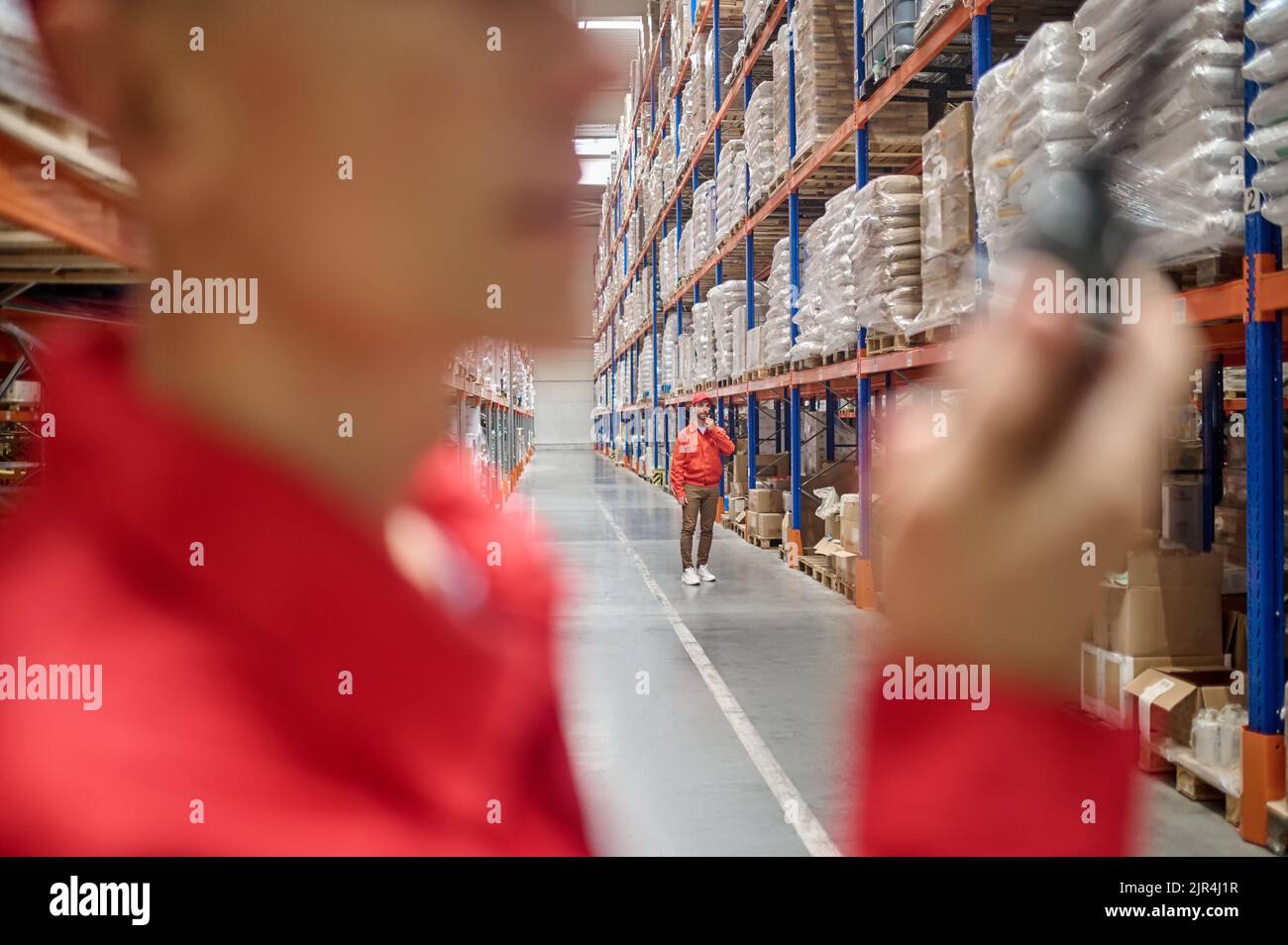 Two warehouse workers communicating over two-way radio Stock Photo