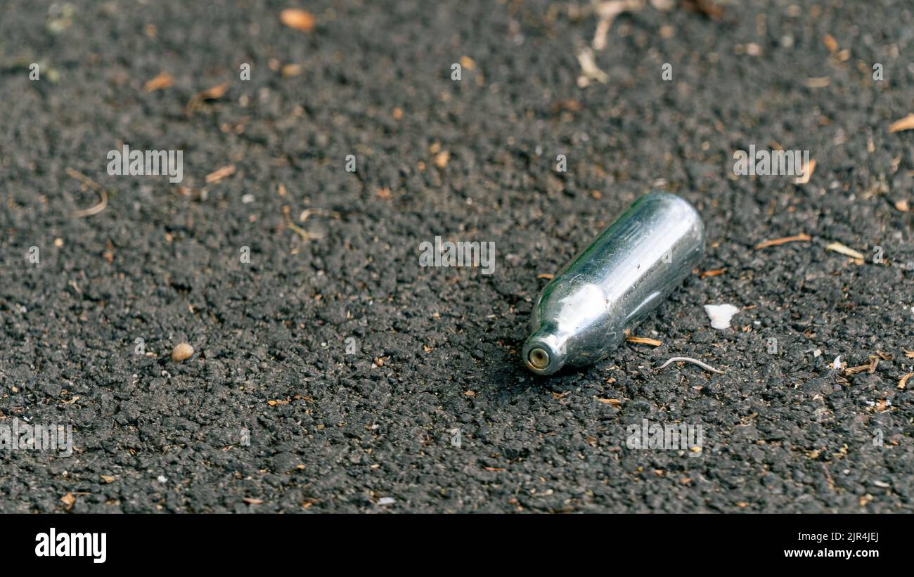 Discarded Nitrous Oxide capsule on tarmac Stock Photo