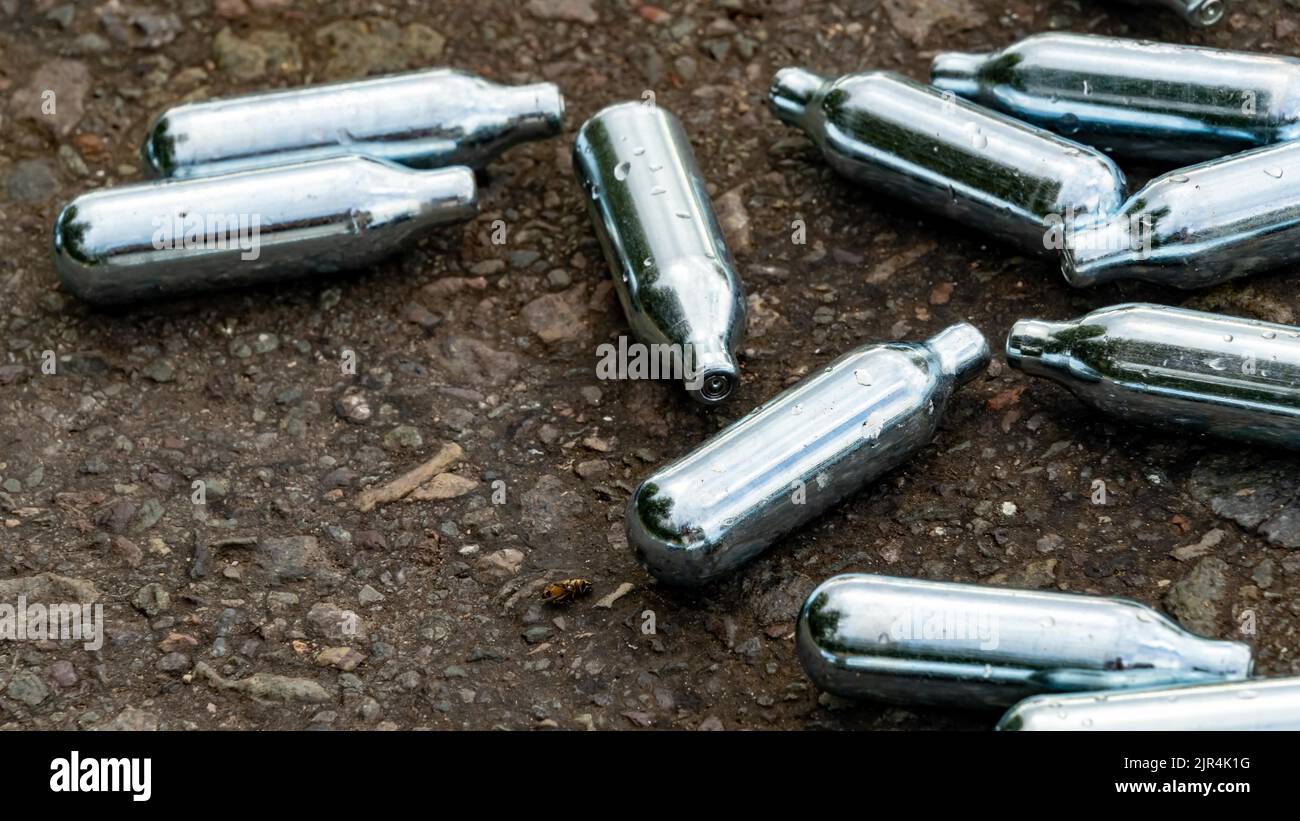 Nitrous Oxide used gas canisters discarded on the roadside Stock Photo