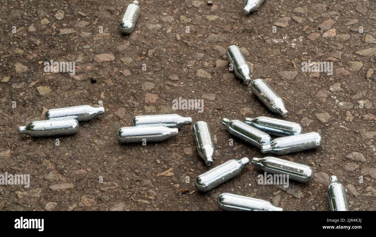 Discarded Nitrous Oxide gas canisters on the roadside Stock Photo