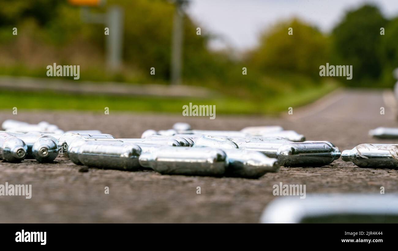 Discarded Nitrous Oxide gas canisters on the roadside Stock Photo