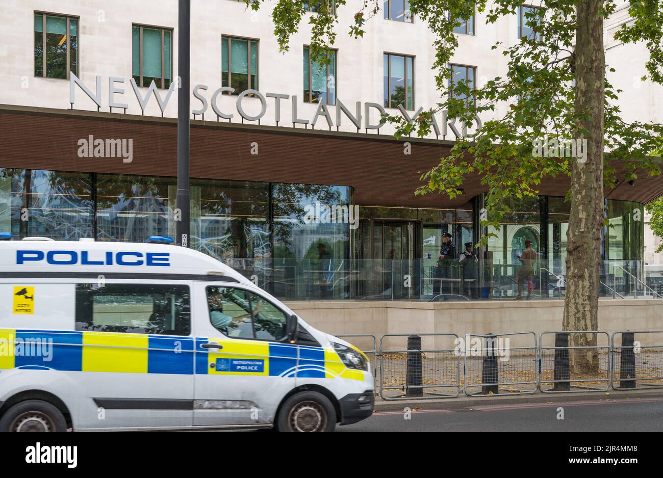 Police van driving past New Scotland Yard Metropolitan Police headquarters on Victoria Embankment, Westminster, London, England, UK Stock Photo