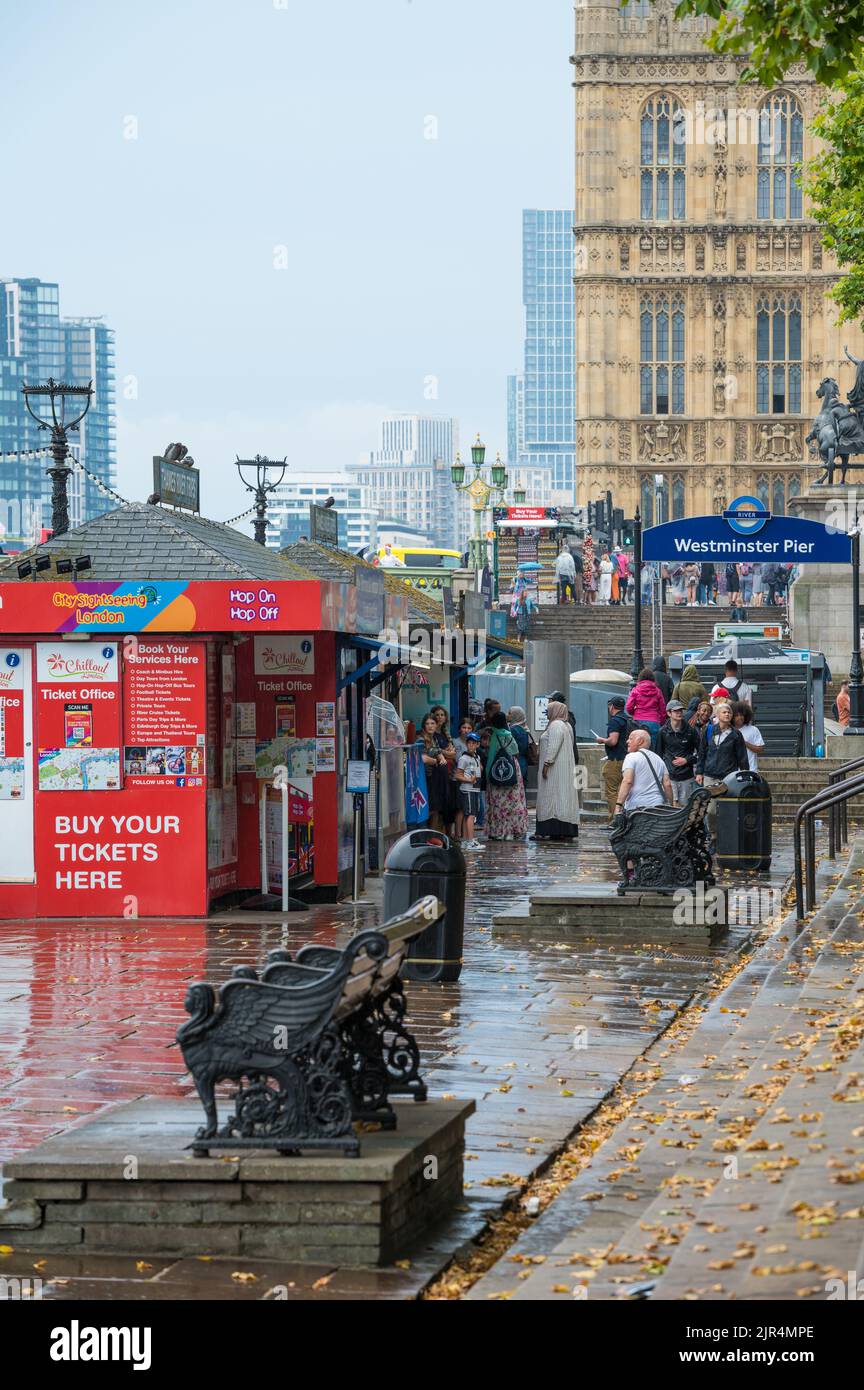 Tourists and sightseers at the tour ticket sales booths on a rainy day at Westminster Pier. London, England, UK. Stock Photo