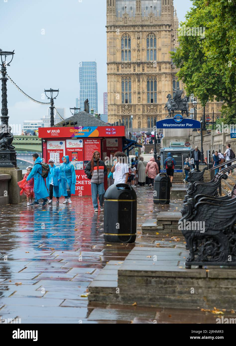 Tourists and sightseers at the tour ticket sales booths on a rainy day at Westminster Pier. London, England, UK. Stock Photo