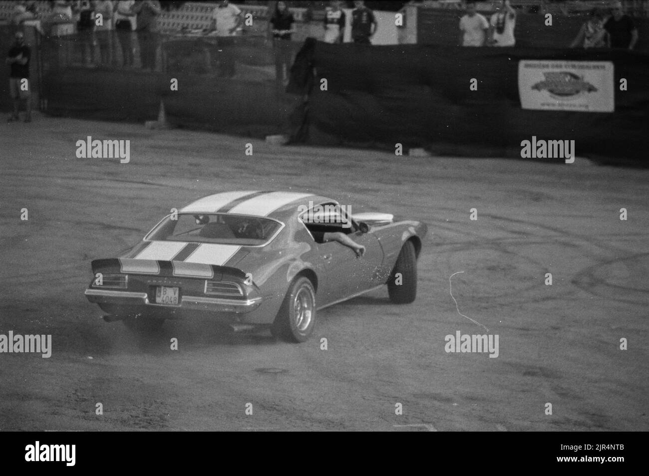 A grayscale shot of Pontiac Firebird Trans AM car driven on a dirt raod Stock Photo
