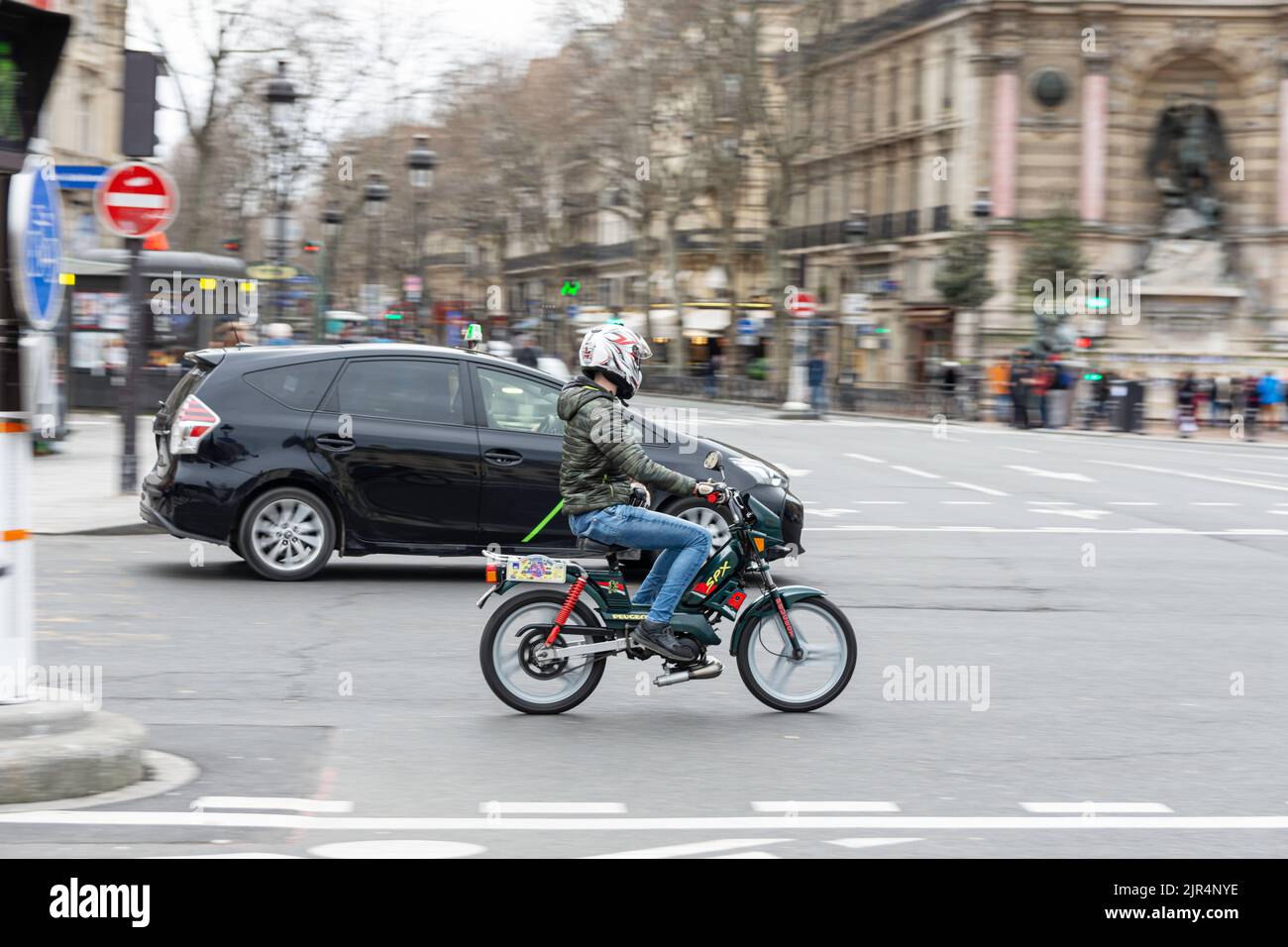 A man driving an old Peugeot SPX moped on the street Stock Photo