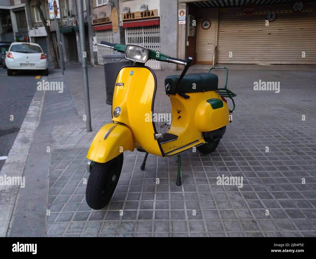 A closeup of a classic yellow Piaggio Vespa scooter on the street Stock Photo