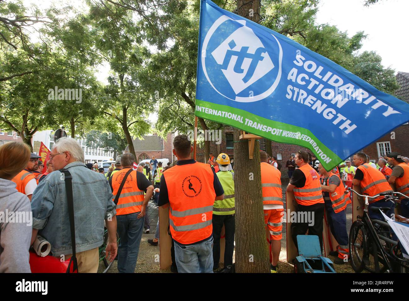 Bremen, Germany. 22nd Aug, 2022. Striking port workers and rally participants stand together holding a flag of itf (International Transport Workers Federation) during a rally on the collective bargaining talks between Verdi and the port companies. The union Verdi and the port companies have resumed their collective bargaining talks on Monday (August 22, 2022) in Bremen. Credit: Bodo Marks/dpa/Alamy Live News Stock Photo