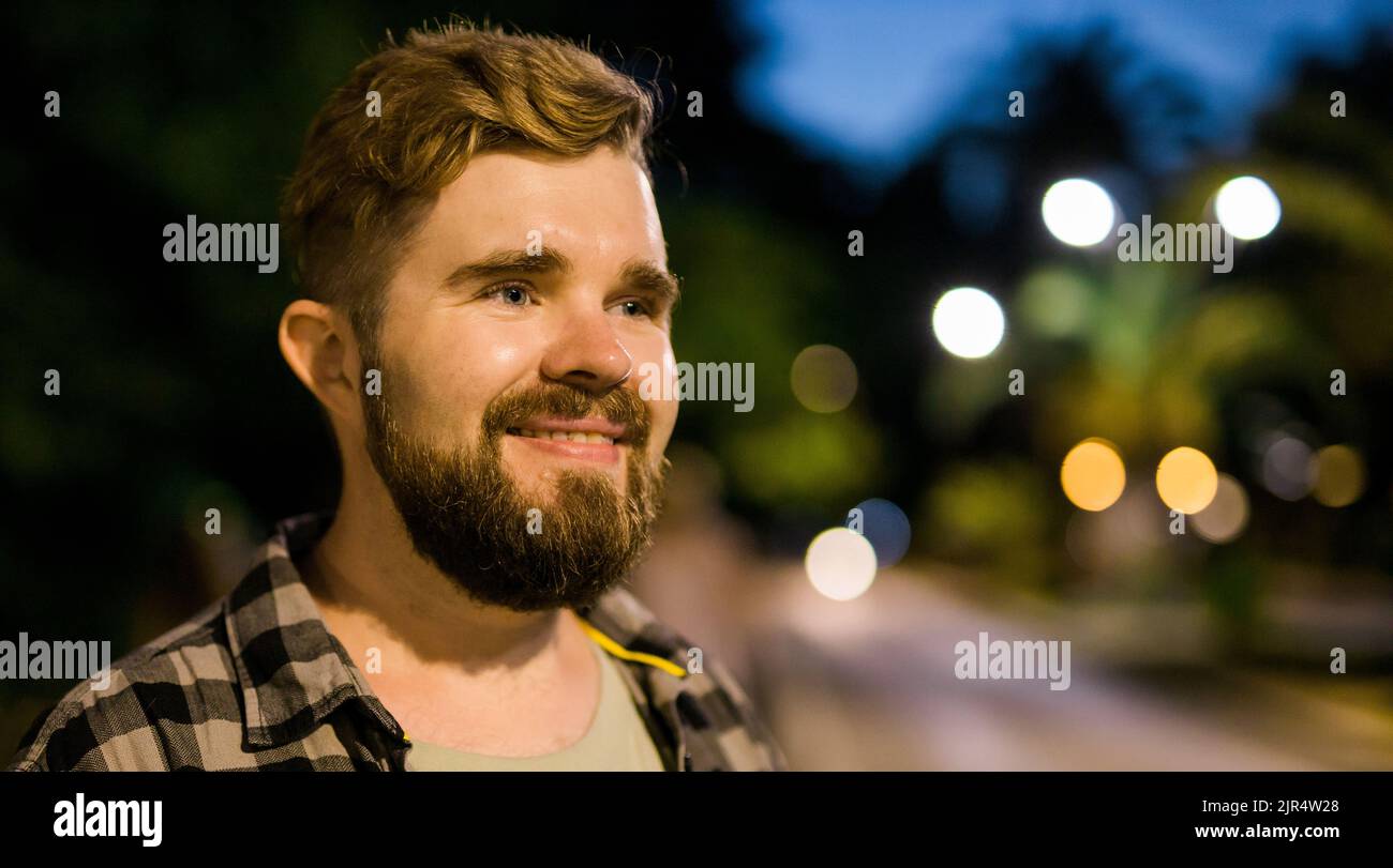 Banner portrait of man standing in night city street with copy space and place for text. Confident happy guy. Close-up portrait Stock Photo