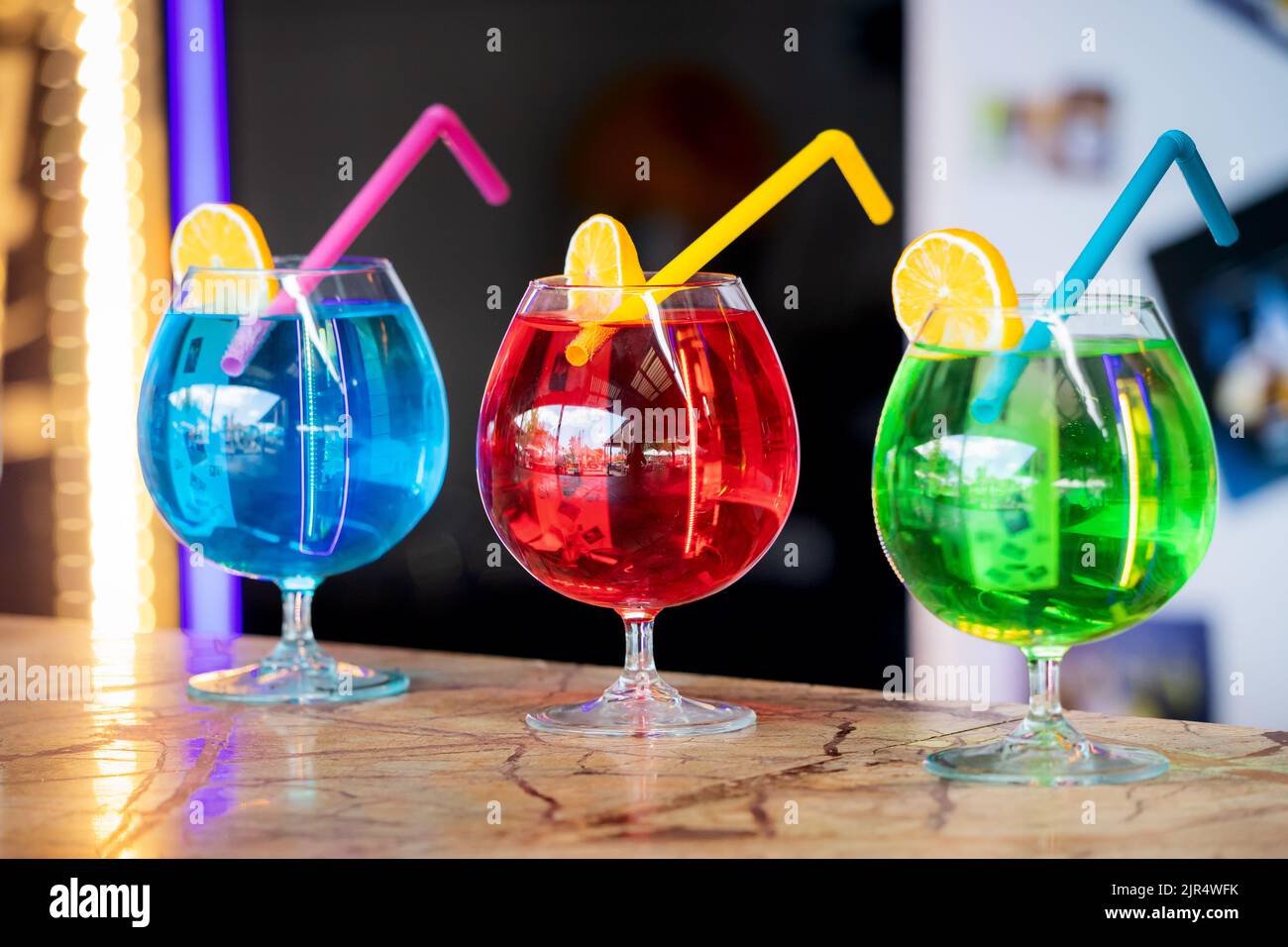 Three colorful bright cocktails with a straw and a slice of lemon. Chemical composition and