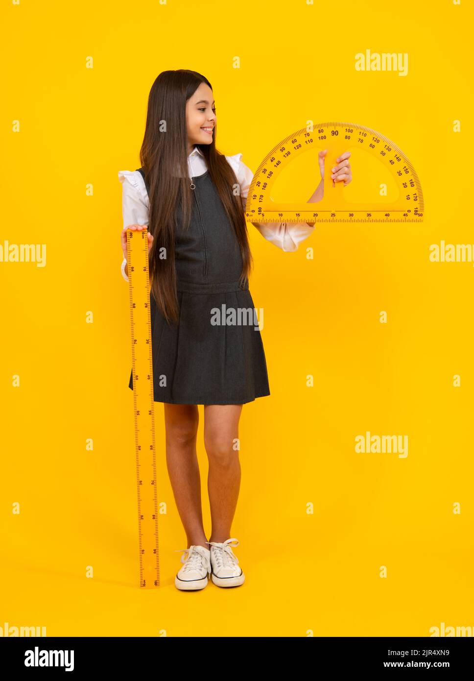 Back to school. School girl hold ruler measuring isolated on yellow ...