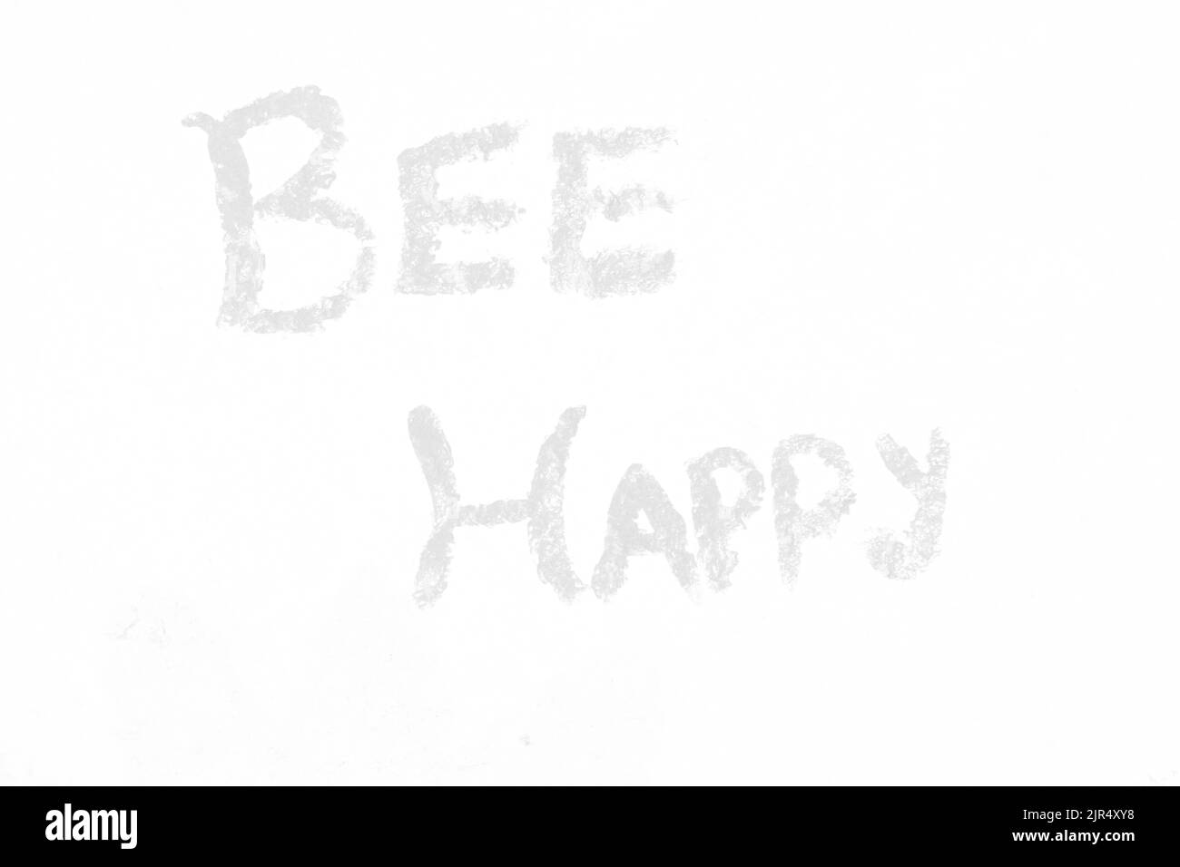 Bee happy painted on a rock as a beautiful garden decoration in a faded black and white monochrome. Stock Photo