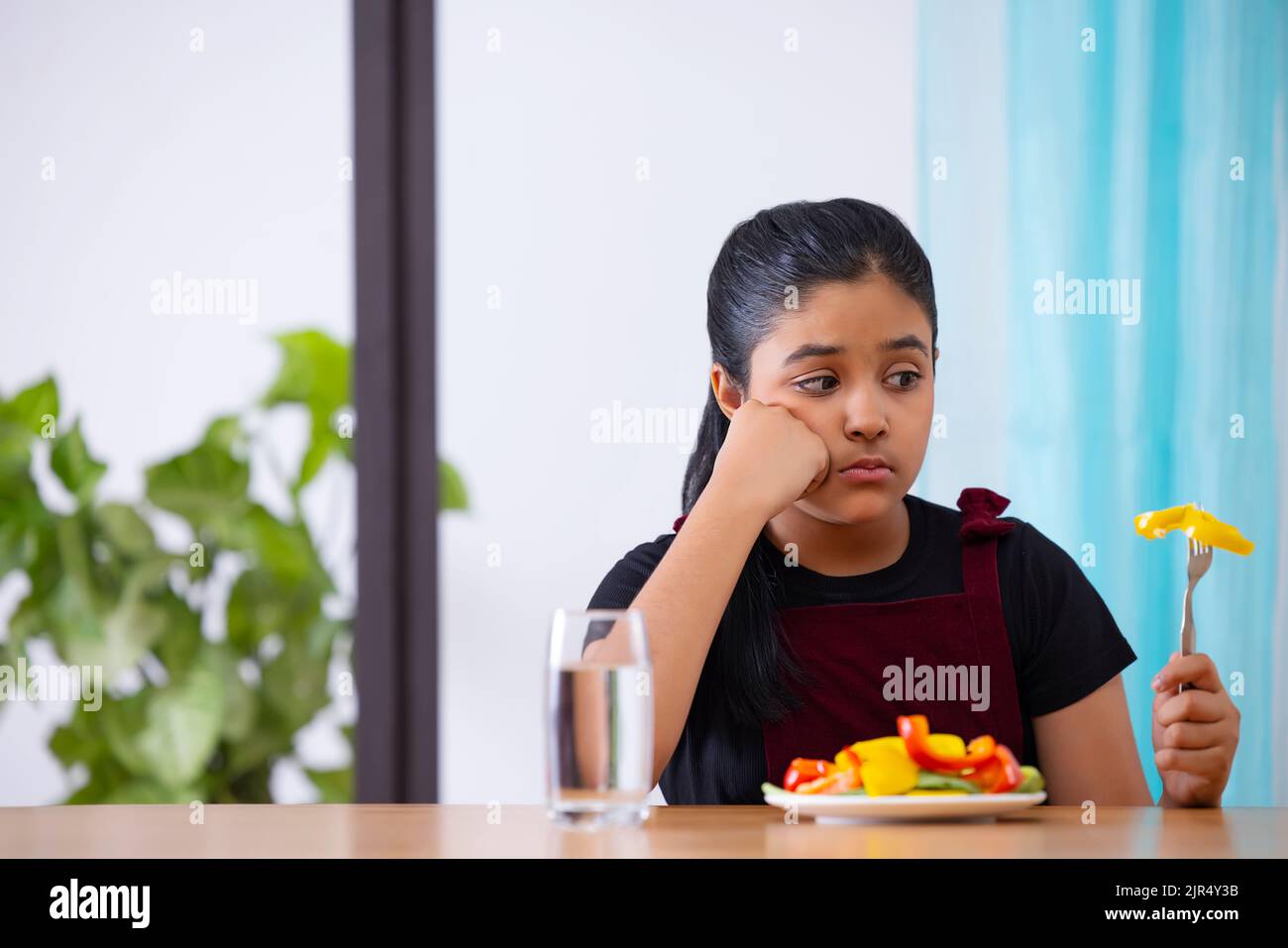 Portrait of a little girl expressing unhappiness over a plate of vegetable salad Stock Photo