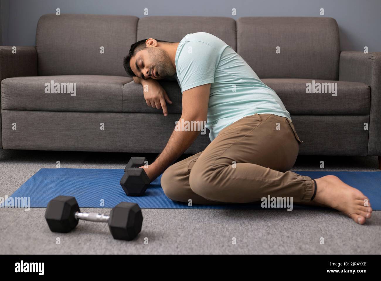 Portrait of tired young man leaning his head on sofa during exercise in