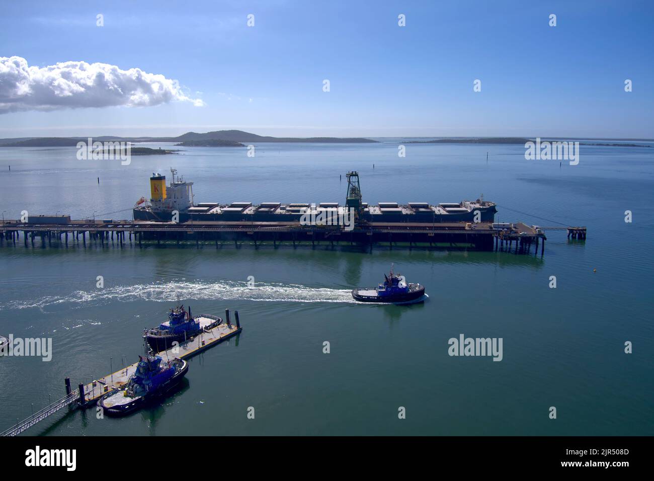 Aerial of tugboat passing the RG Tanna Coal Terminal at Port of Gladstone Queensland Australia Stock Photo