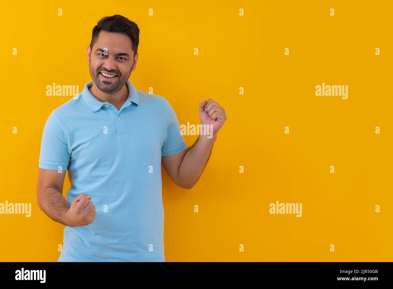 Portrait of happy young man cheering with raising his fists Stock Photo