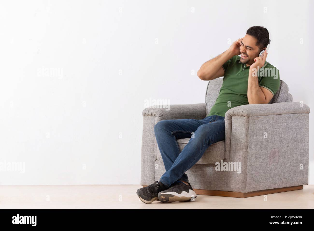 Young man listening music on headphones and having fun while sitting on sofa Stock Photo