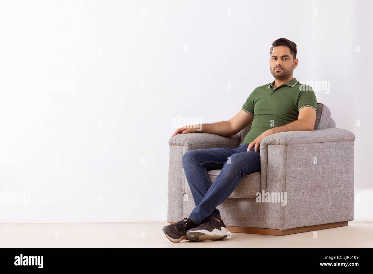 Portrait of young man looking at camera while sitting on sofa Stock Photo