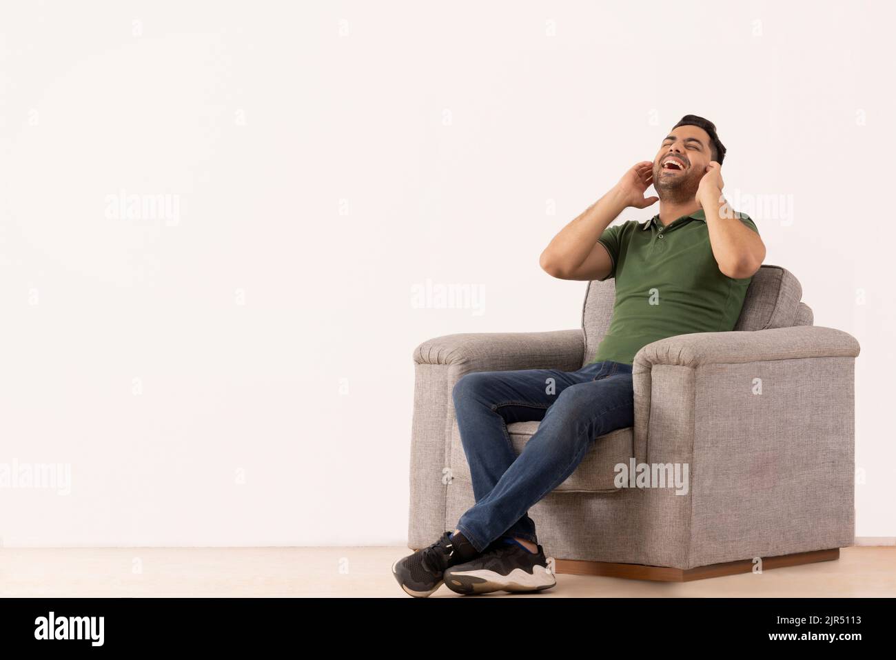 Portrait of young man smiling while sitting on sofa Stock Photo