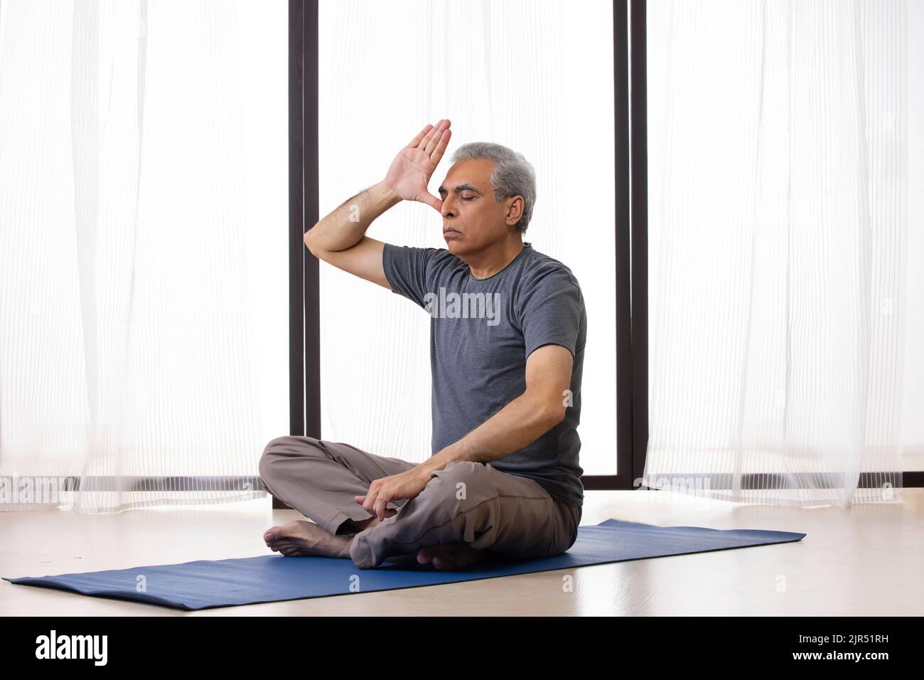 Portrait of an active  senior man doing breathing exercise at home Stock Photo