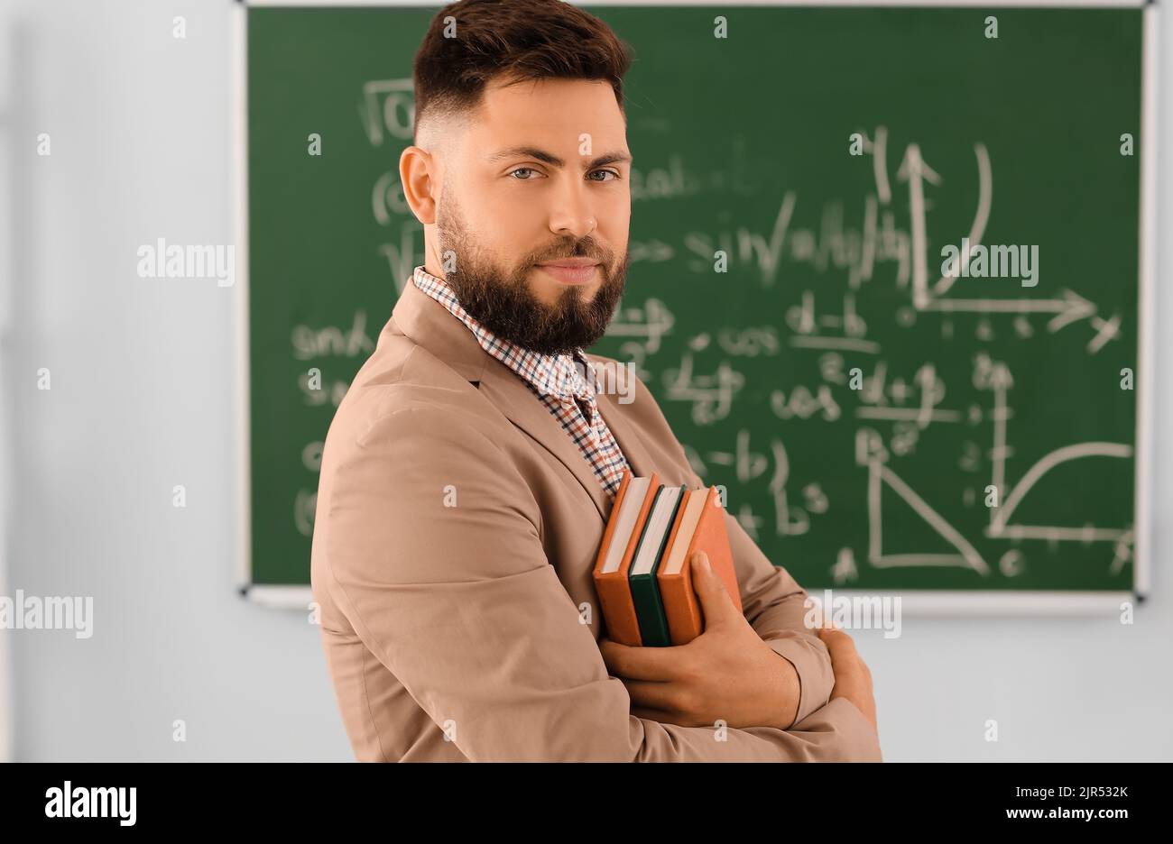 Handsome Math teacher with books in classroom Stock Photo