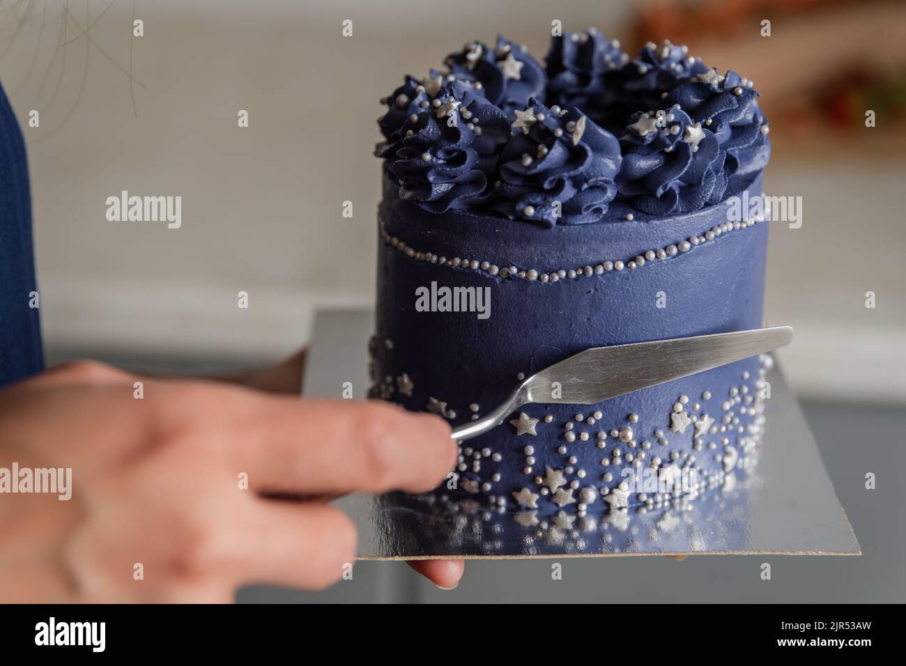 Leveling the cream on the sponge cake with spatula. Stock Photo