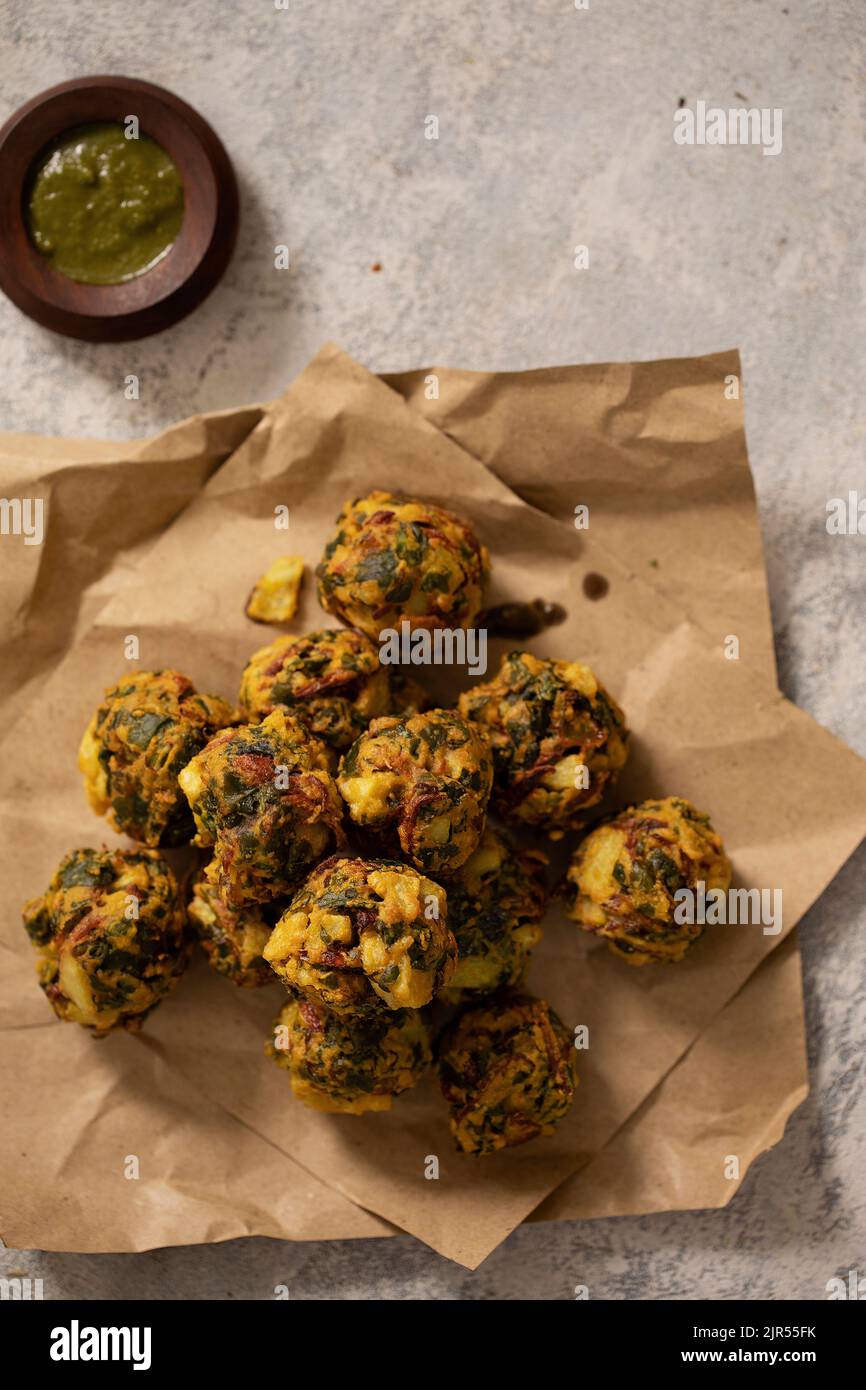DEEP FRIED VEGETABLE PAKORAS SERVED HOT ON SHEETS OF PAPER WITH CHUTNEY Stock Photo