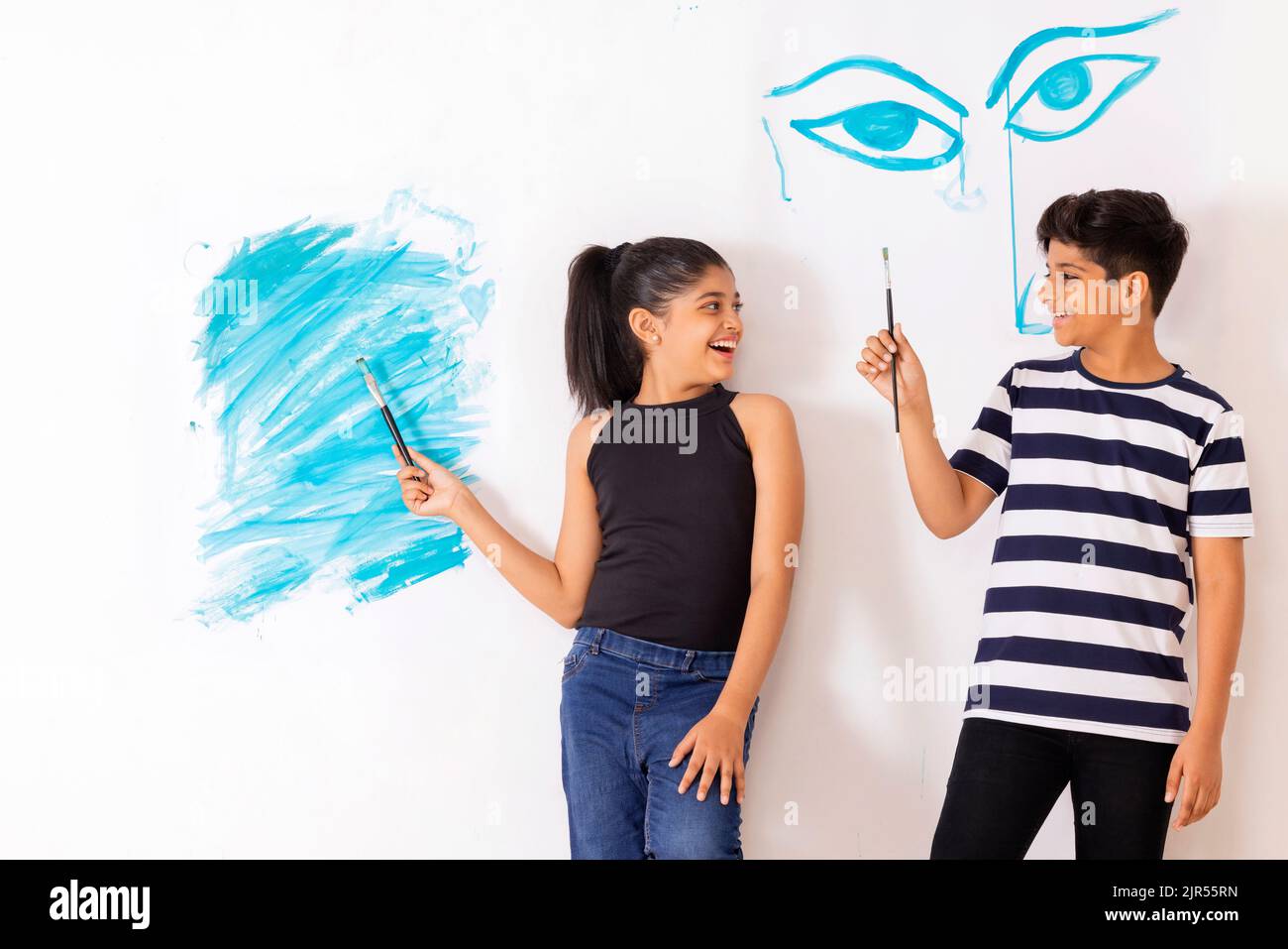 Cheerful children drawing together on white wall Stock Photo - Alamy