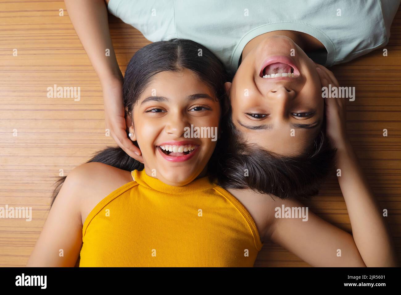 Close-up of boy and girl lying down on wooden floor Stock Photo