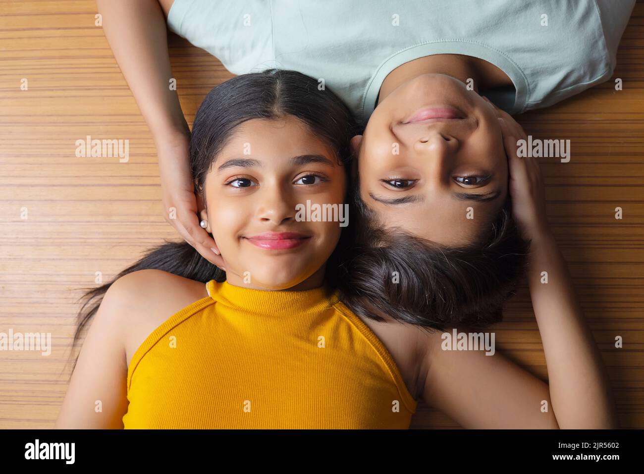 Close-up of boy and girl lying down on wooden floor Stock Photo