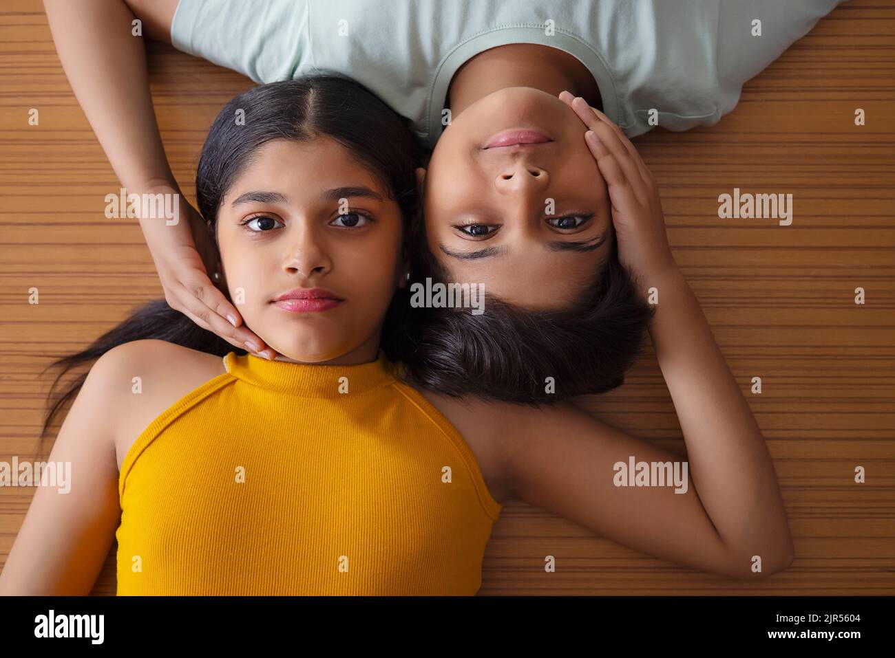 Close-up of boy and girl lying down on wooden floor Stock Photo