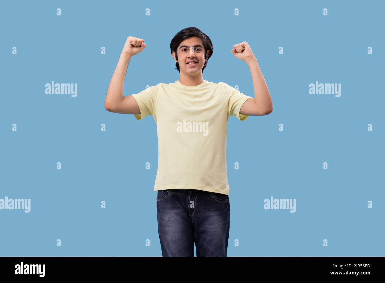 Portrait of a teenage boy cheering against blue background Stock Photo