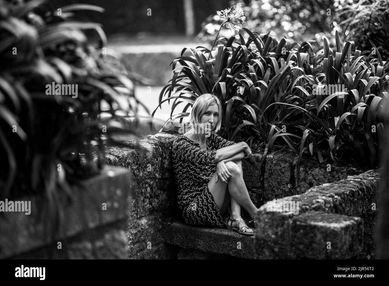A woman sits on a stone bench in old portuguese park. Black and white photo. Stock Photo