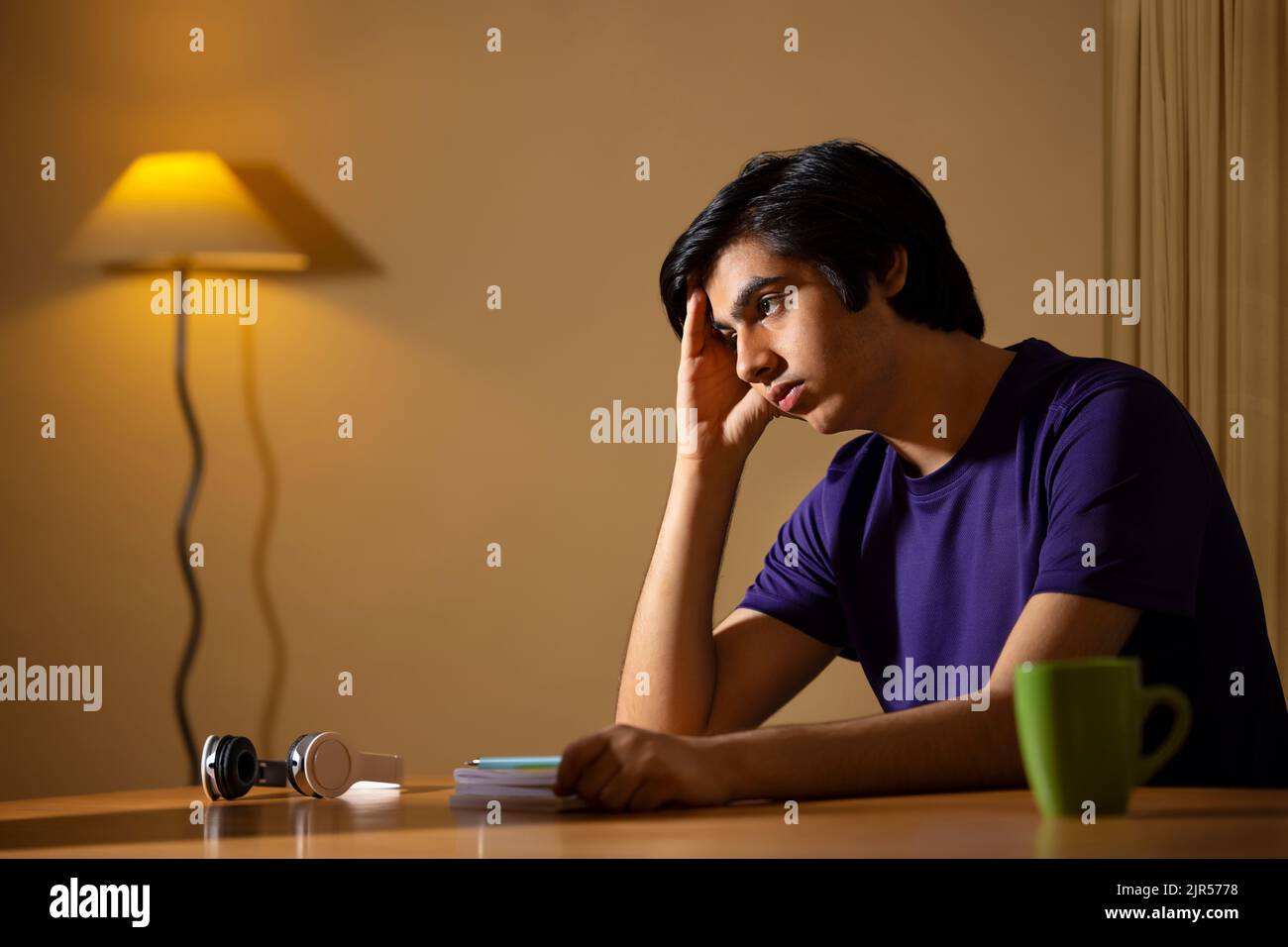 Portrait of a thoughtful teenage boy sitting with hand on head at home Stock Photo Alamy