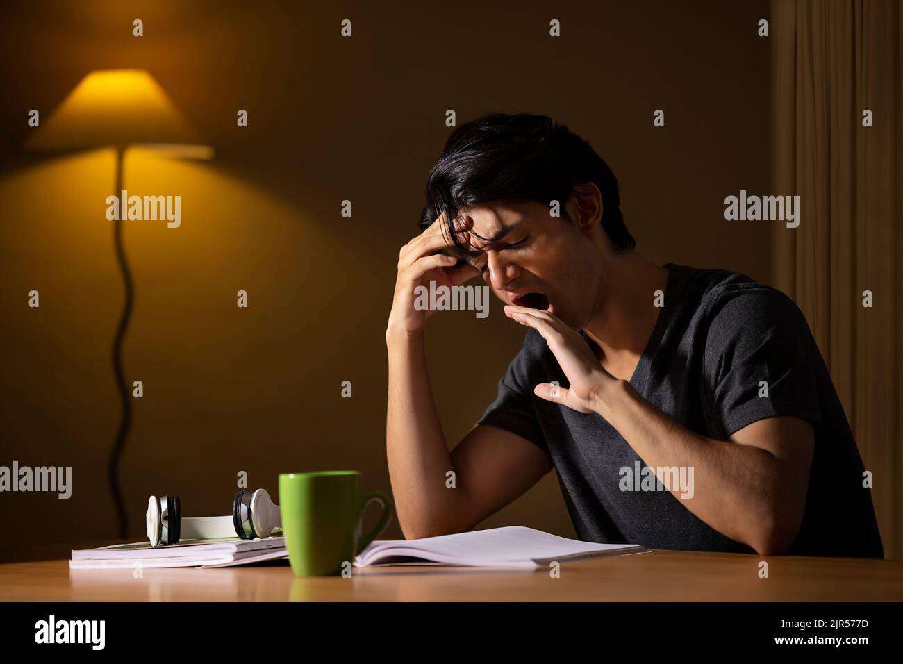 Portrait of an exhausted teenager yawning while studying at home Stock Photo