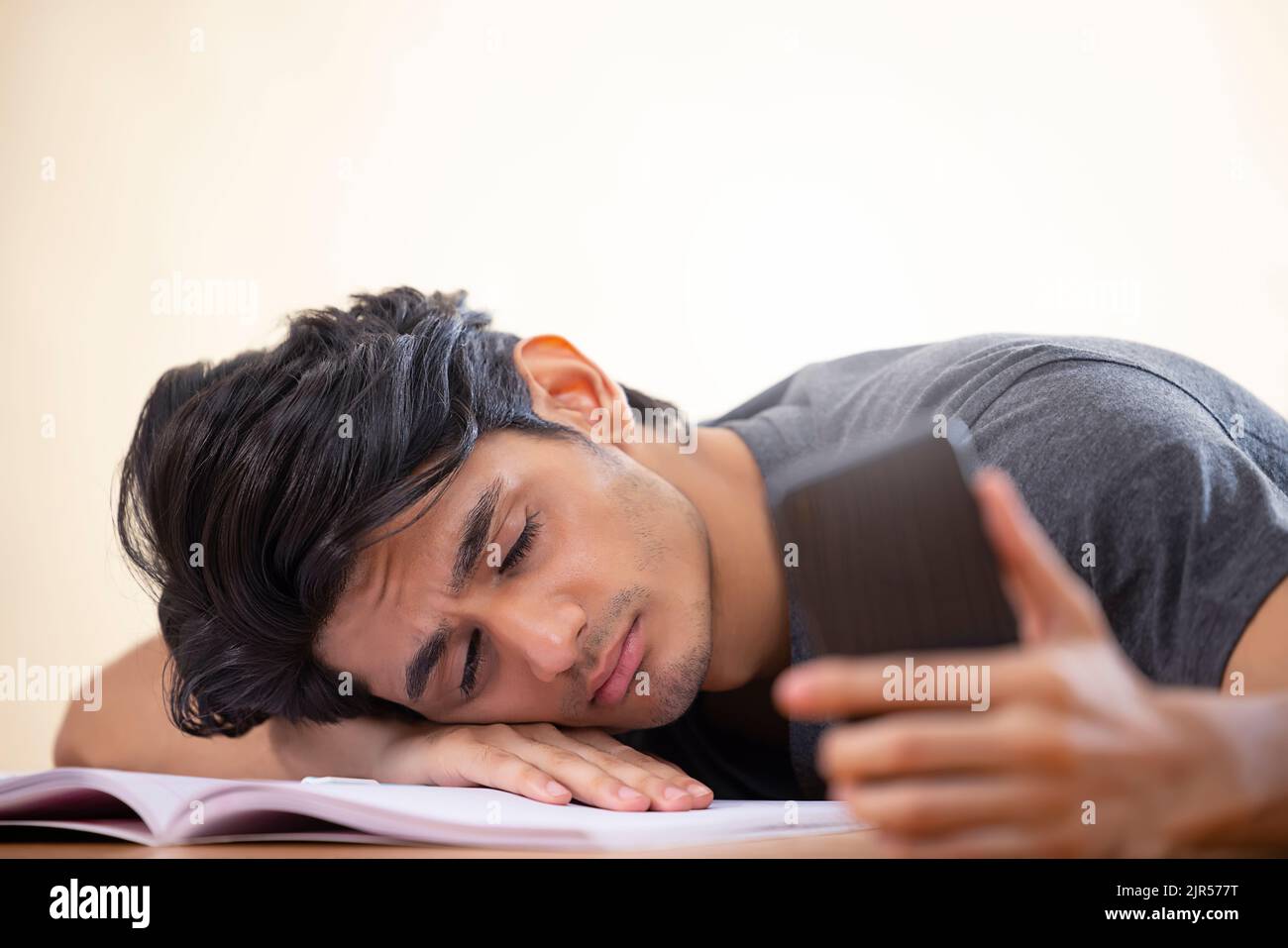 Close-up portrait of a tired teenager sleeping with holding a smartphone Stock Photo