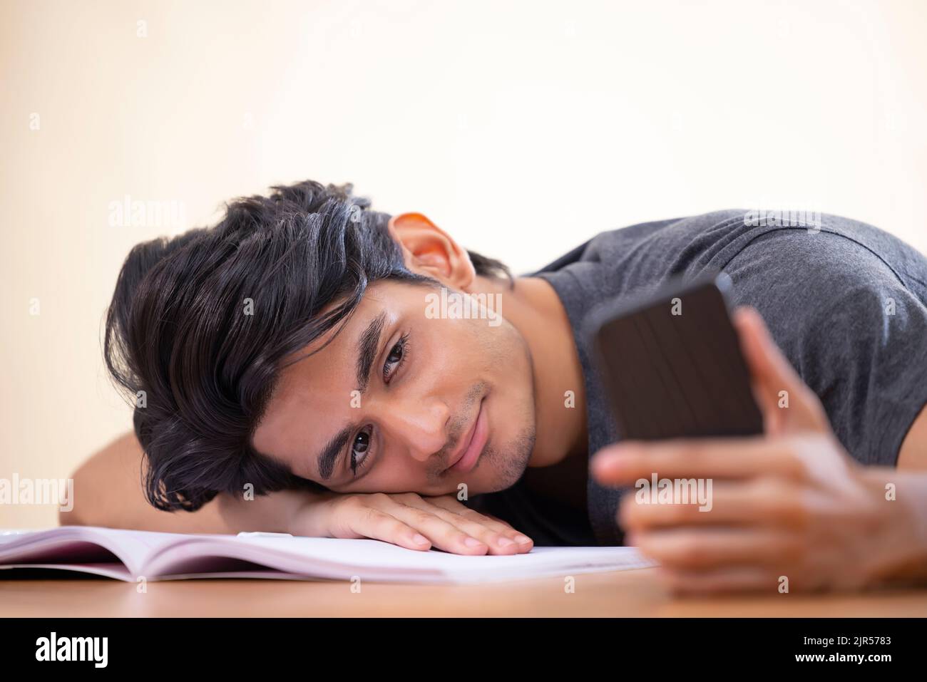 Close-up portrait of a tired teenager leaning head on hand with holding a smartphone Stock Photo