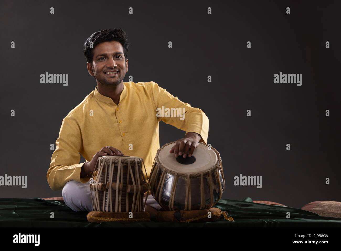 Portrait of cheering young man performing with Tabla on stage Stock Photo