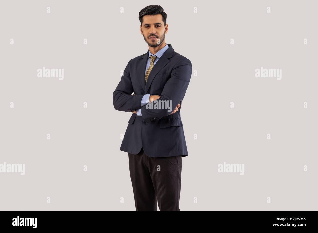 Portrait of a corporate employee in formal business suit standing cross-armed. Stock Photo